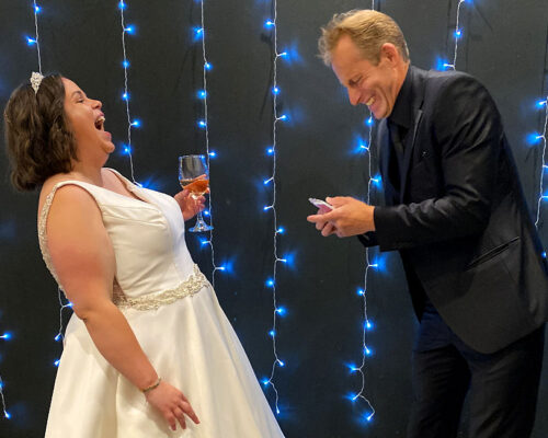 Kat weddgall Brett Sirrell shares a joke with the bride as they both laugh and have fun being entertained by his tricks.