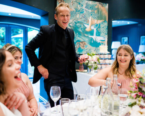 Kat&Phil table weddgall Bridesmaids and Bride laughing and being entertained by Brett during the wedding breakfast and at the dinner table.