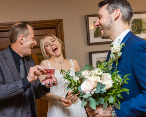 Cotswold House Hotel Magician Bride and groom laughing out loud as Brett magically produces a card in a manor hotel in Gloucestershire.