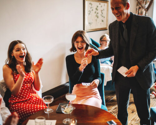Wedding guests reacting in amazement to close-up magic performed by Brett Sirrell at a Cotswolds event
