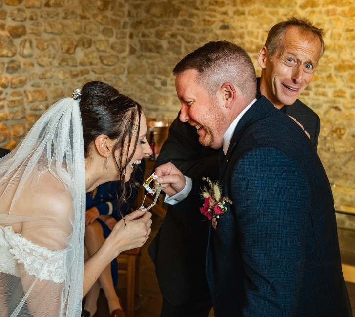 Professional wedding magician performing mind-blowing close-up magic for a laughing bride and groom during their reception
