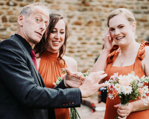 dodford barn bridemaids Bridesmaids laughing and having fun during the drinks reception, as Brett, magician, performs his close up magic