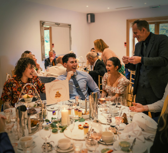 Cotswold House Hotel guests laughing and connecting over close-up magic with Brett Sirrell during a wedding breakfast